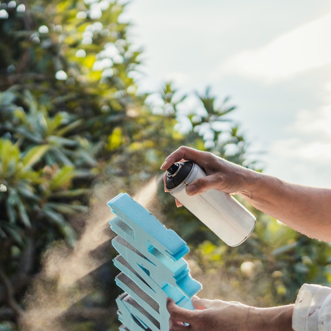 Woman painting polystyrene letters with paint on spray outdoors